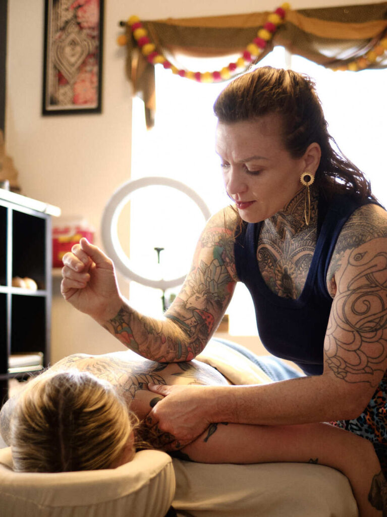 A woman massaging another woman who is face down on a massage table.