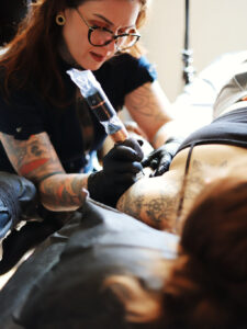 A woman tattooing another woman