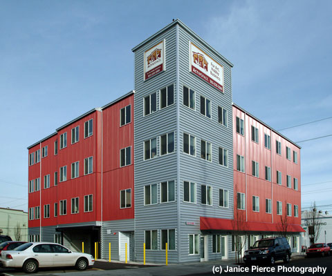 Image of the ActivSpace building on SE Main in Portland, Oregon. A large red warehouse style four story building. 