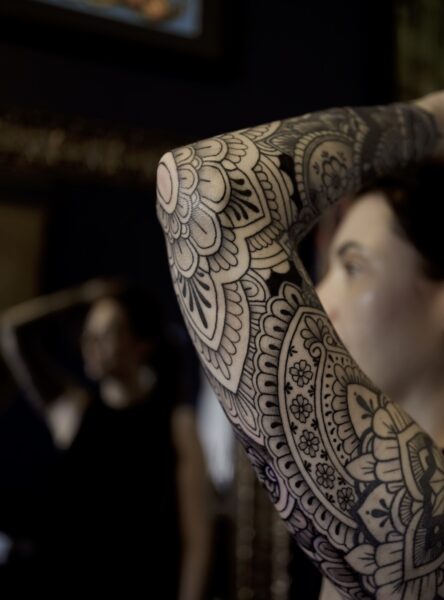 Ornamental tattoo on a woman's arm with a focus on the elbow mandala