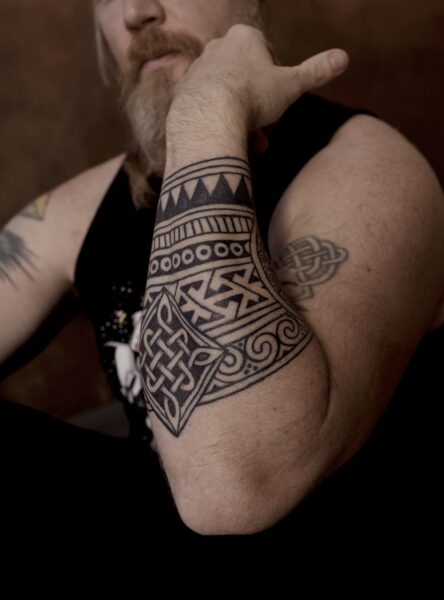 Image of a man with a celtic knotwork and pictish pattern ornamental blackwork tattoo on his forearm.