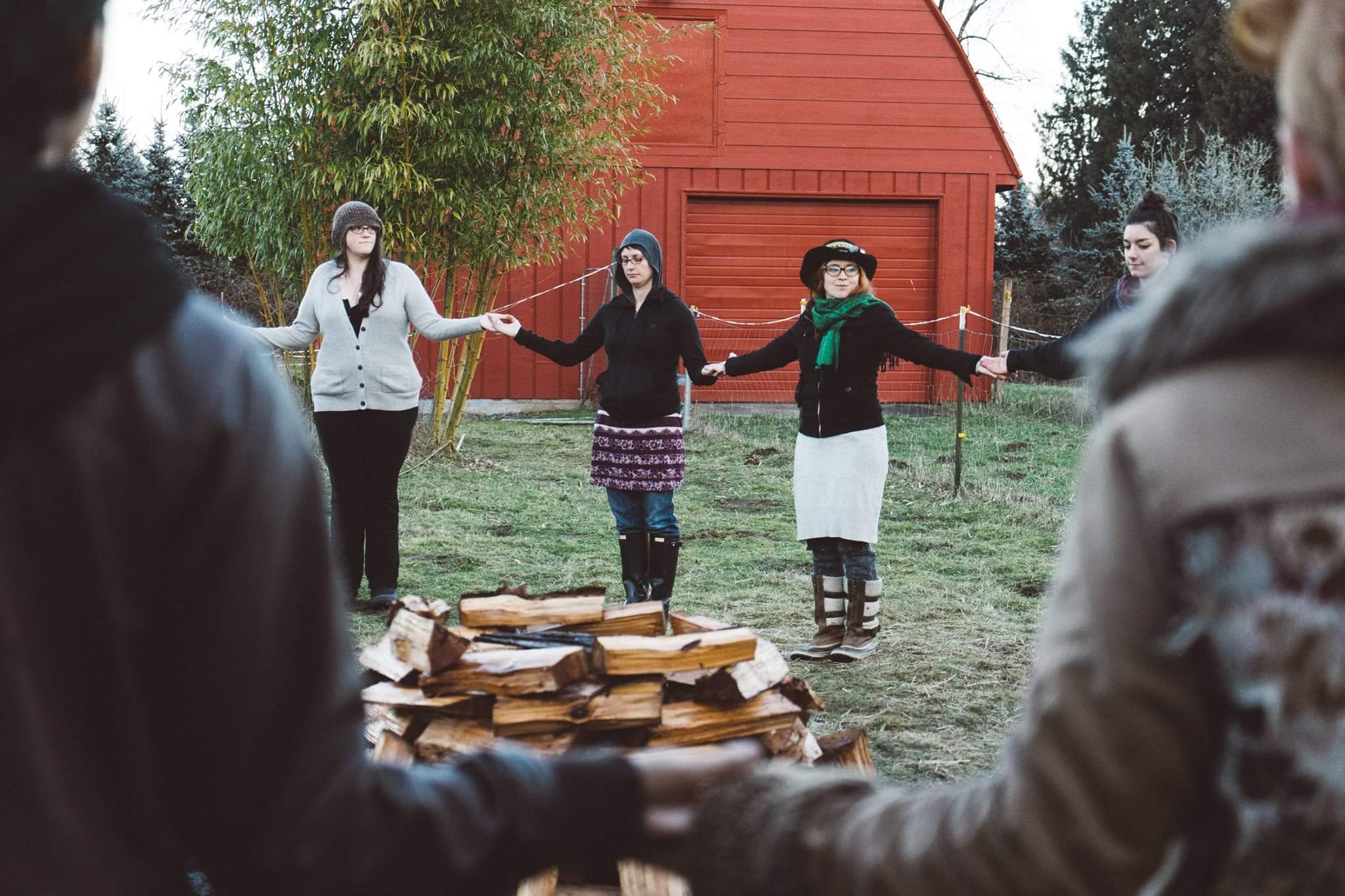 Women standing in a circle around a fire that is about to be lit