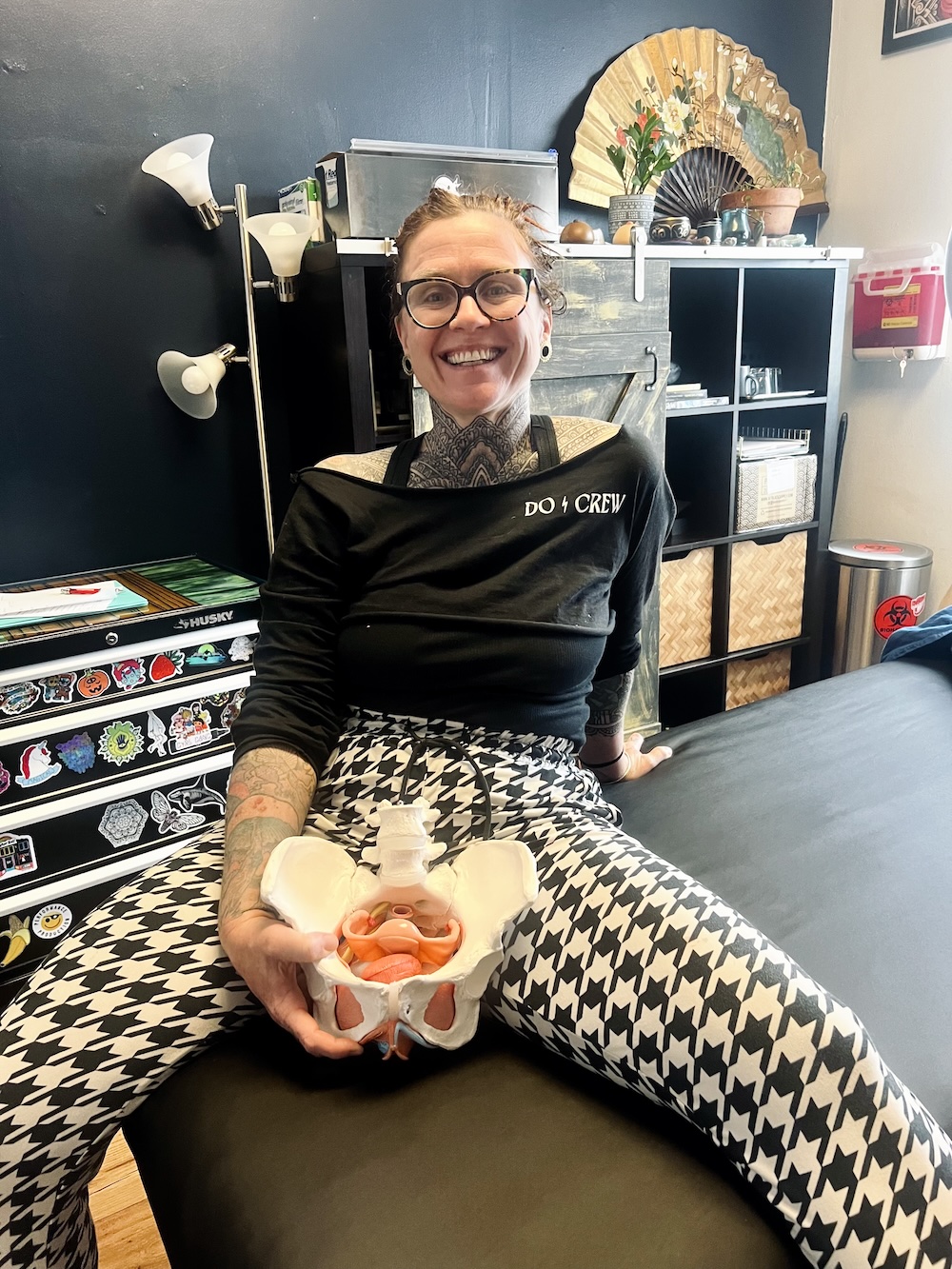 Woman with anatomical model of the female pelvis